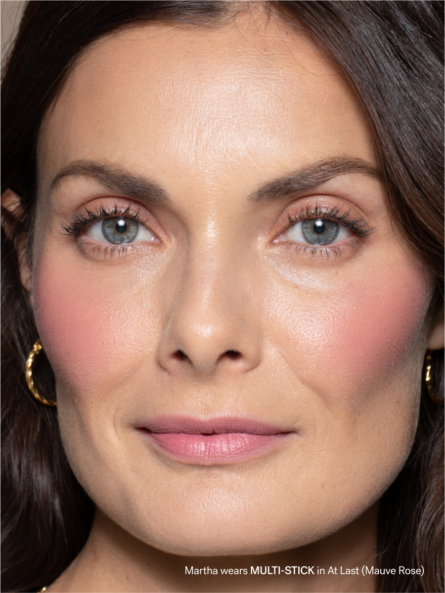 Close-up of a woman's face with makeup, wearing gold earrings.